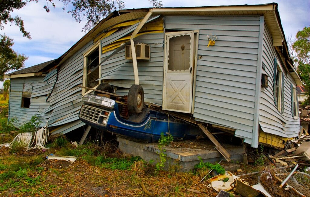 20 Reasons Not to Live in the US (2024) 8 A blue truck under a destroyed house after a typhoon.