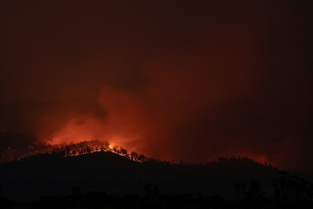 19 Reasons Not To Move To Australia In 2024 2 A bushfire far on a mountain in Australia.
