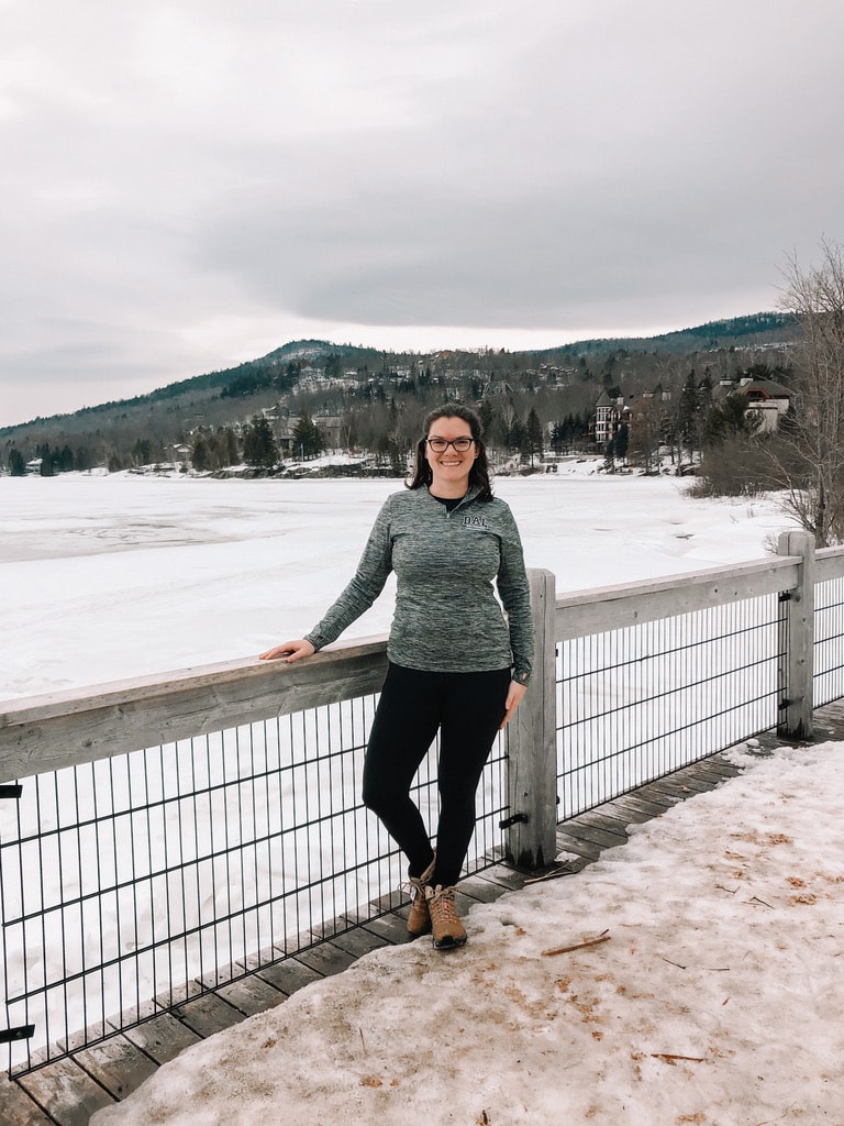 Cost of Living in Canada vs US (Complete 2024 Comparison) 8 Nina wearing a grey sweater leaning on a a fence during winter.