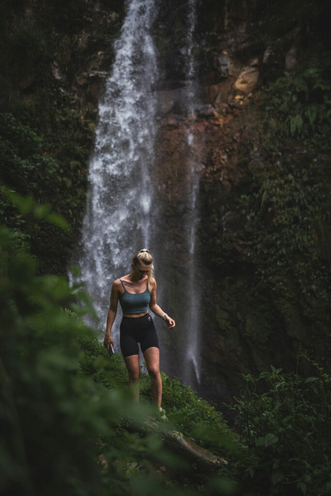 Top 17 Countries With Retirement Visas (2024 Guidelines) 2 A woman walking on the edge of a trail with a waterfall behind her.