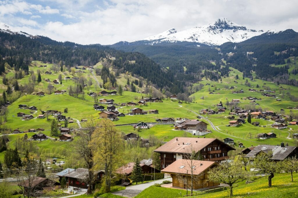13 Countries That Will Pay You To Move There (Expat’s Picks) 4 A village in Switzerland with a few houses annd a view of the Alps.