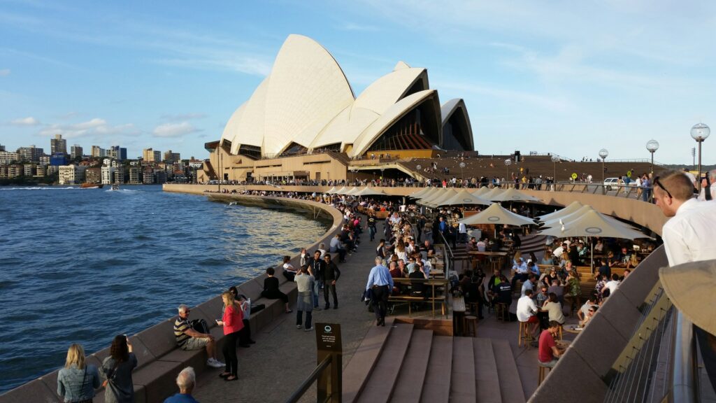 19 Reasons Not To Move To Australia In 2024 7 The bay at Sydney Opera House with lots of people sitting on the chairs and tables while enjoying the view.