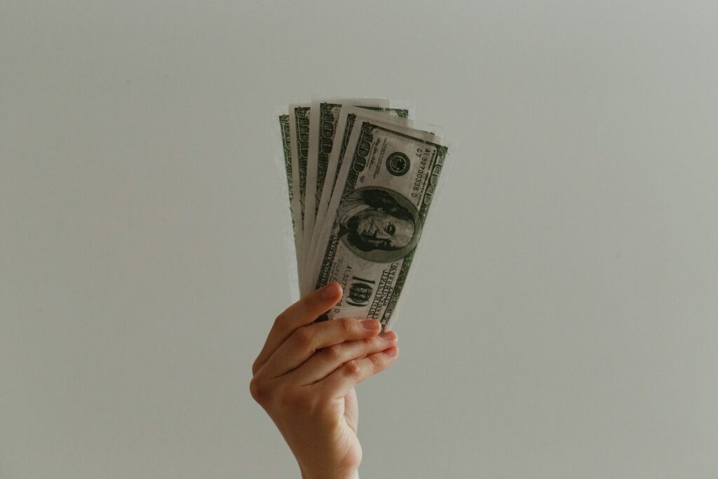 Cost of Living in Canada vs US (Complete 2024 Comparison) 6 A hand holding 5 100 dollar bills.