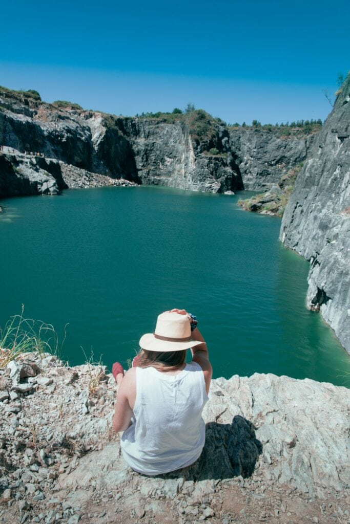 Top 17 Countries With Retirement Visas (2024 Guidelines) 8 A woman wearing a white hat sitting on the edge of a rock formation overlooking the lake in Uruguay.