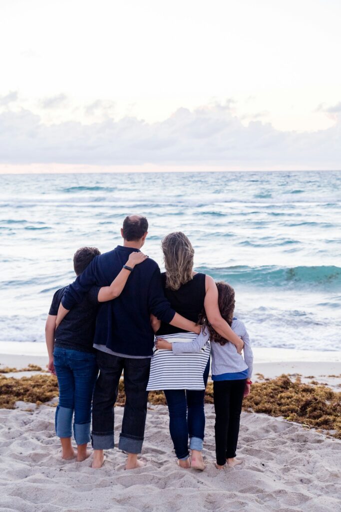 Cost of Living in Canada vs US (Complete 2024 Comparison) 1 A photo of a family of four barefoot in the sand while looking at the sea.