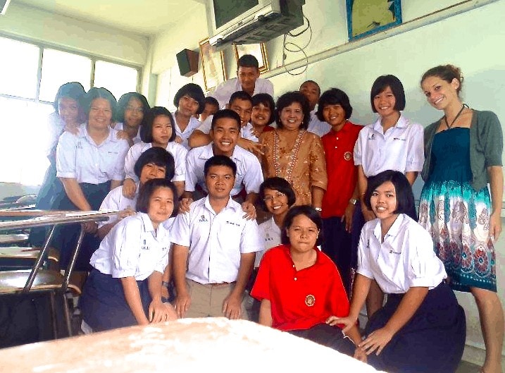 9 Easiest Jobs to Do While Traveling 3 A joyful group of students and teachers posing for a photo in a classroom setting, showcasing a sense of community and learning.