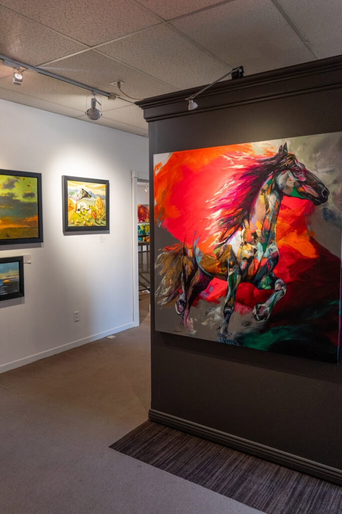 My 4 Day Charlevoix Itinerary to Recharge in Quebec 2 Interior of Galerie d’Art Iris featuring colorful modern paintings including a striking horse artwork on a dark wall. Exploring local art galleries adds a cultural touch to your Charlevoix trip.