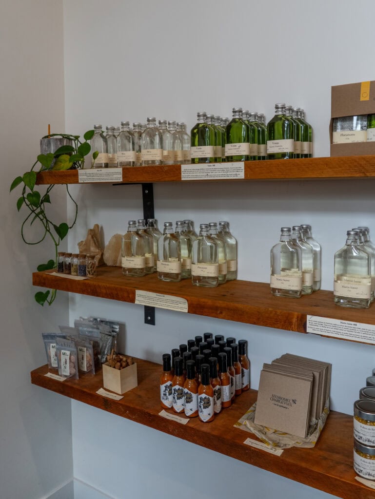 My 4 Day Charlevoix Itinerary to Recharge in Quebec 3 Wooden shelves lined with bottles of local honey wine, spirits, and small packaged goods inside Hydromel Charlevoix tasting room.